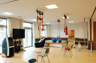 入居者向けレクリエーション・活動スペース。吊り下げおもちゃと広い床が見える。